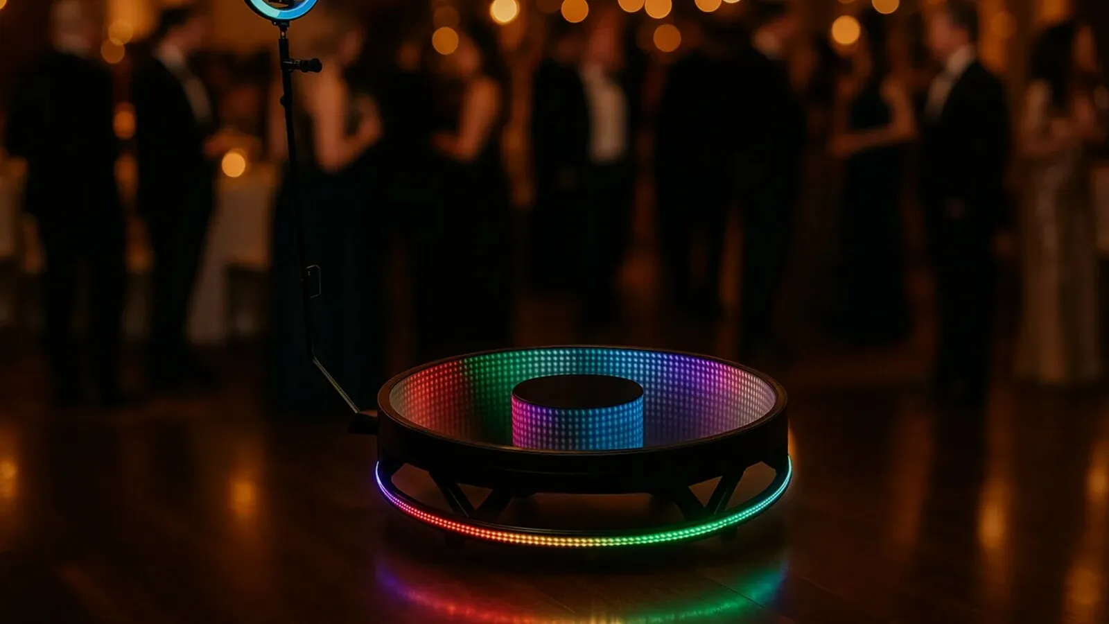 Guests on a 360 photo booth platform surrounded by an LED ring at a party
