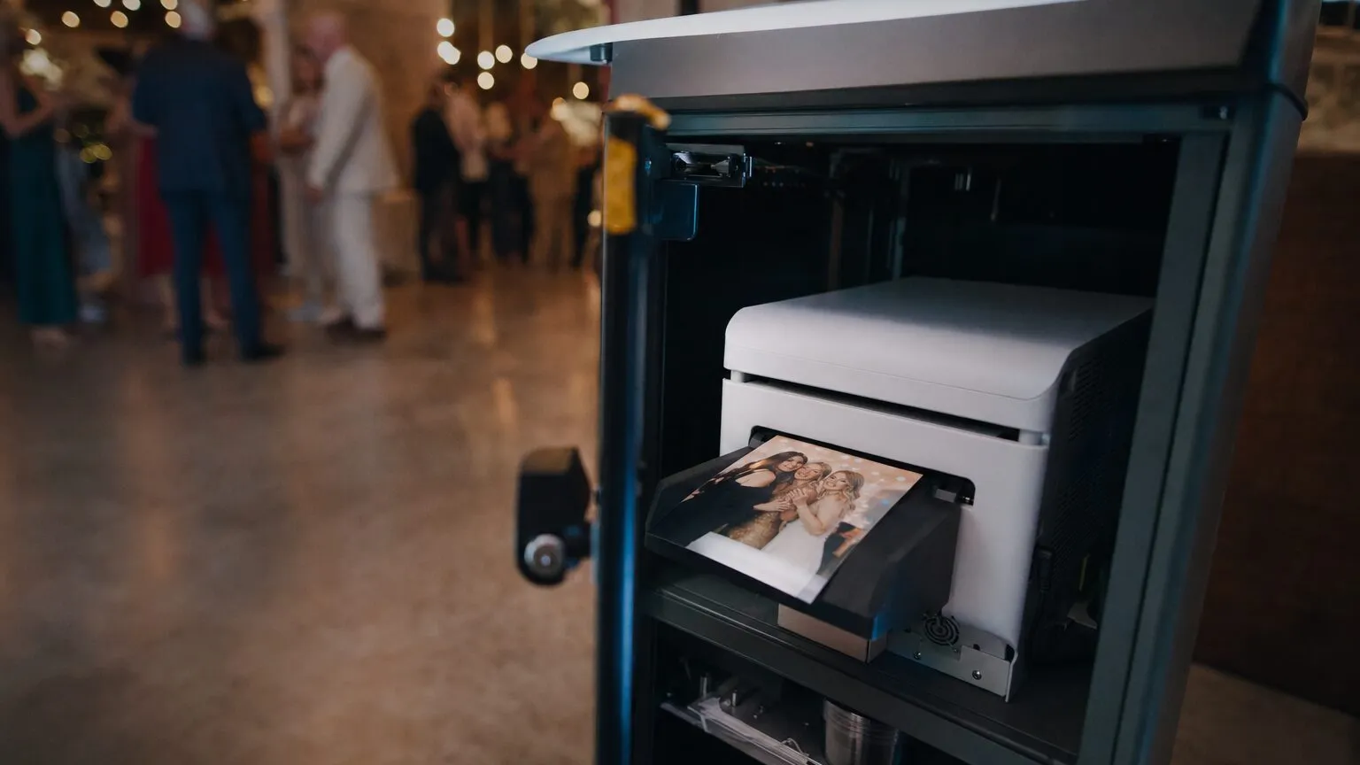 Dye sublimation photo printer inside an open photo booth column, printing at a wedding